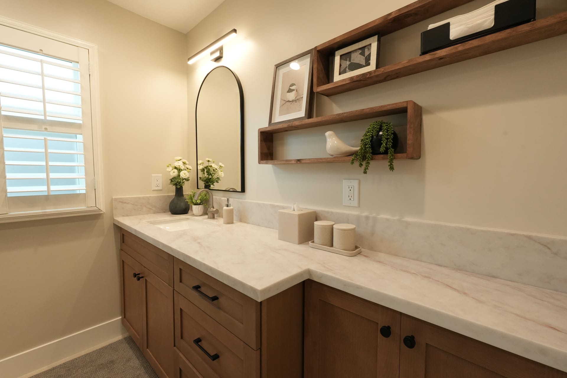 double-sink vanity with white countertop, arched mirror, and wood drawers