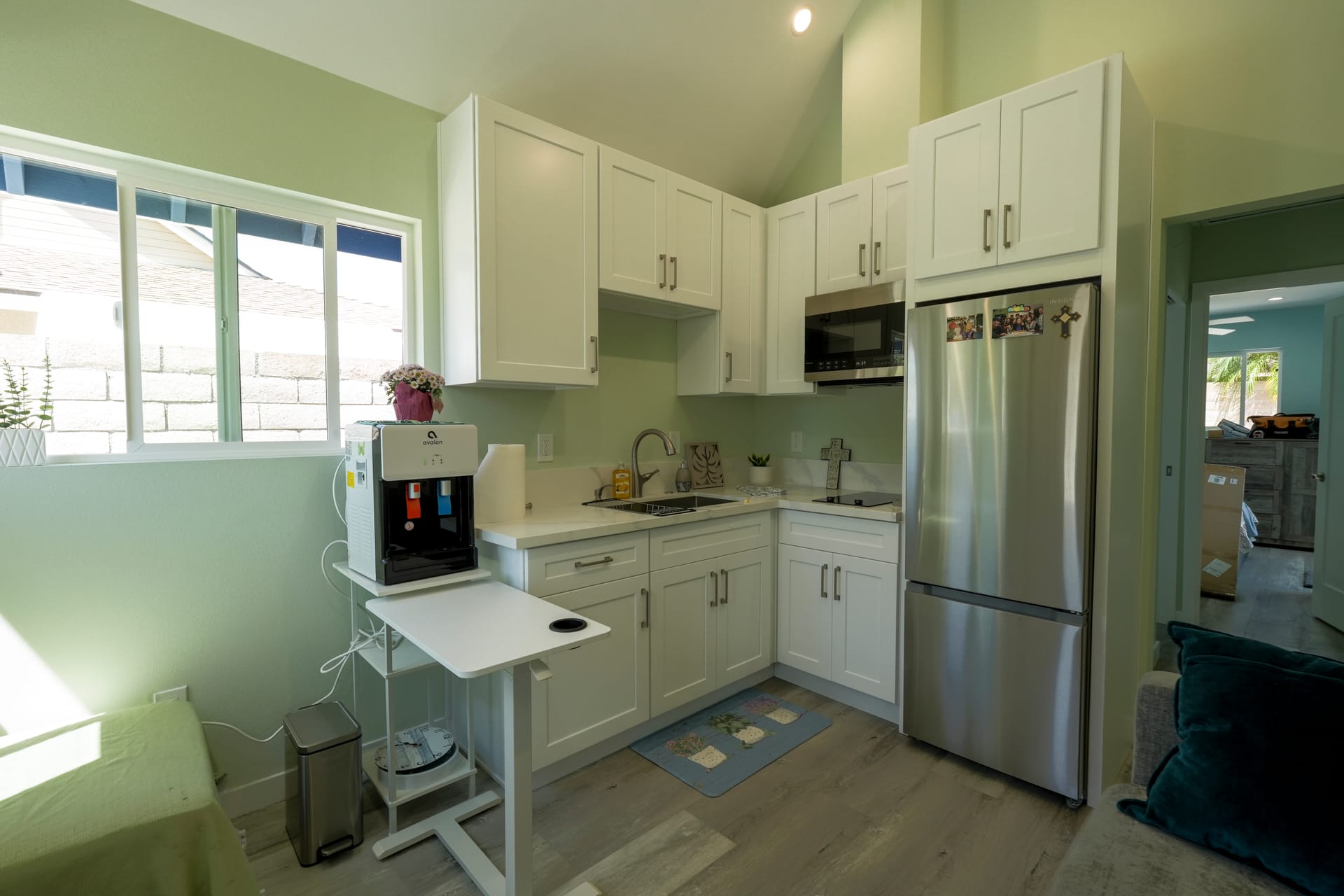 white L-shaped kitchen with upper cabinets, stainless refrigerator, and window
