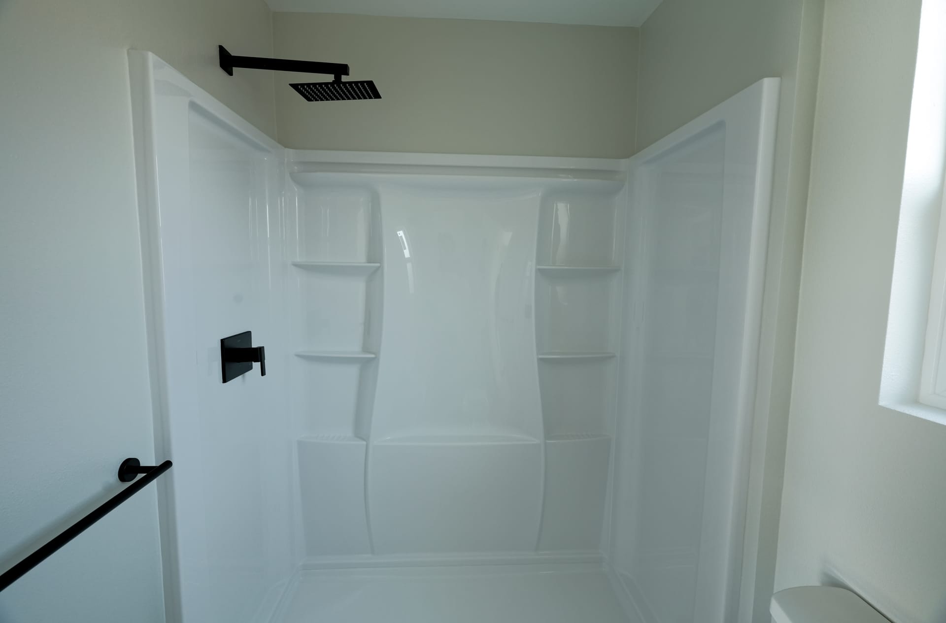 bathroom shower with white tile surround and dark fixtures