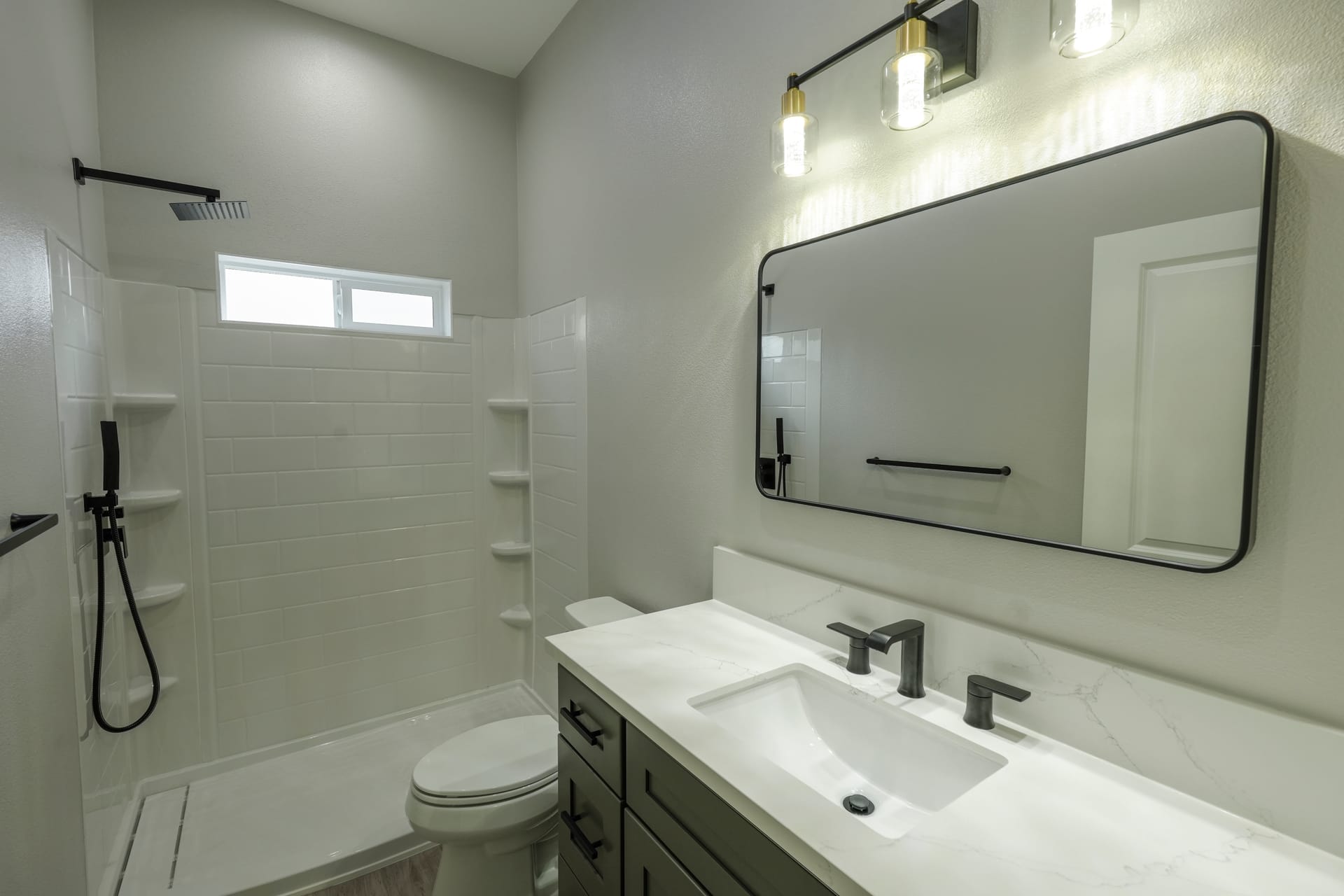 Bathroom vanity beside a glass shower and tiled walls