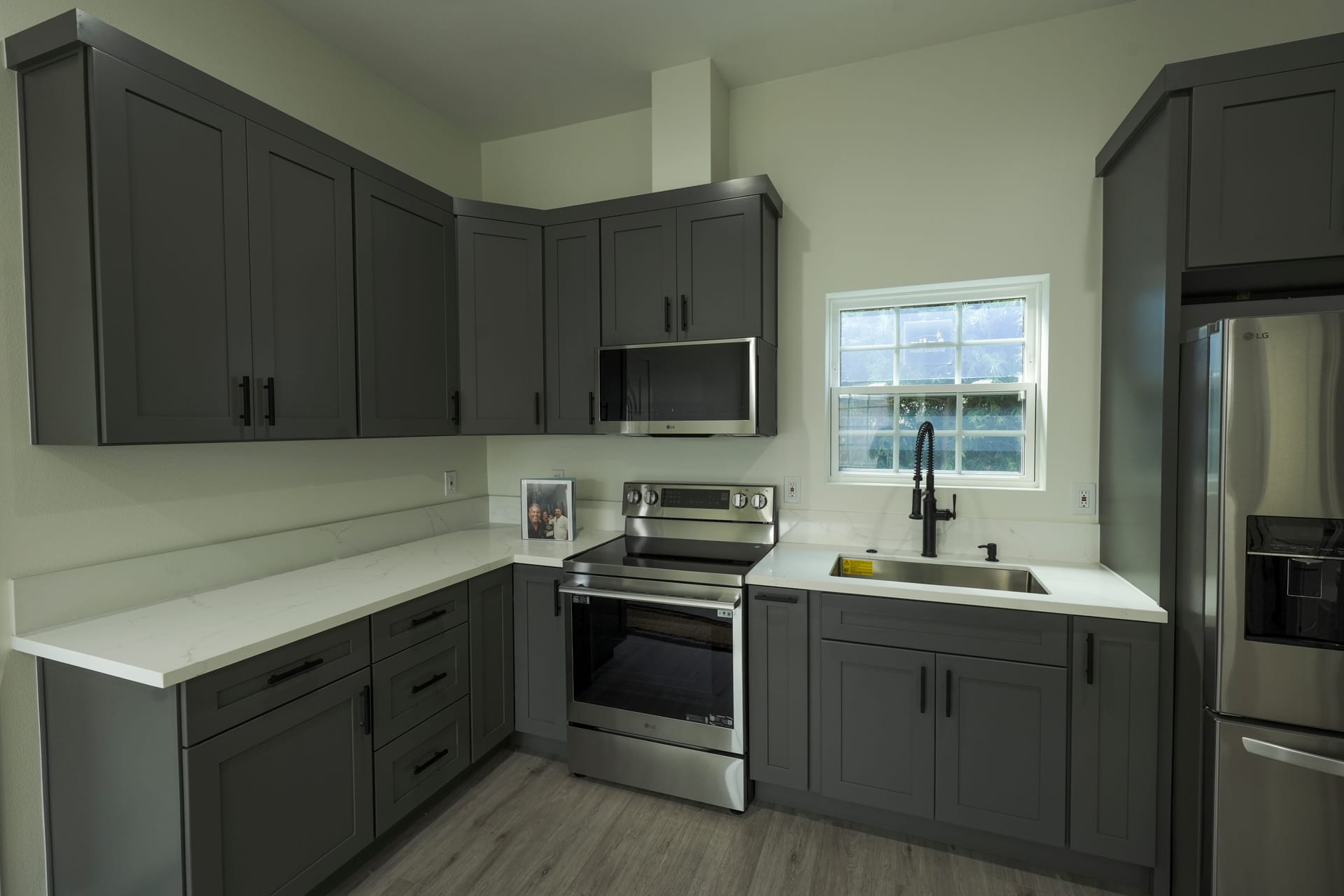 Gray kitchen cabinets with a central window and pale countertops
