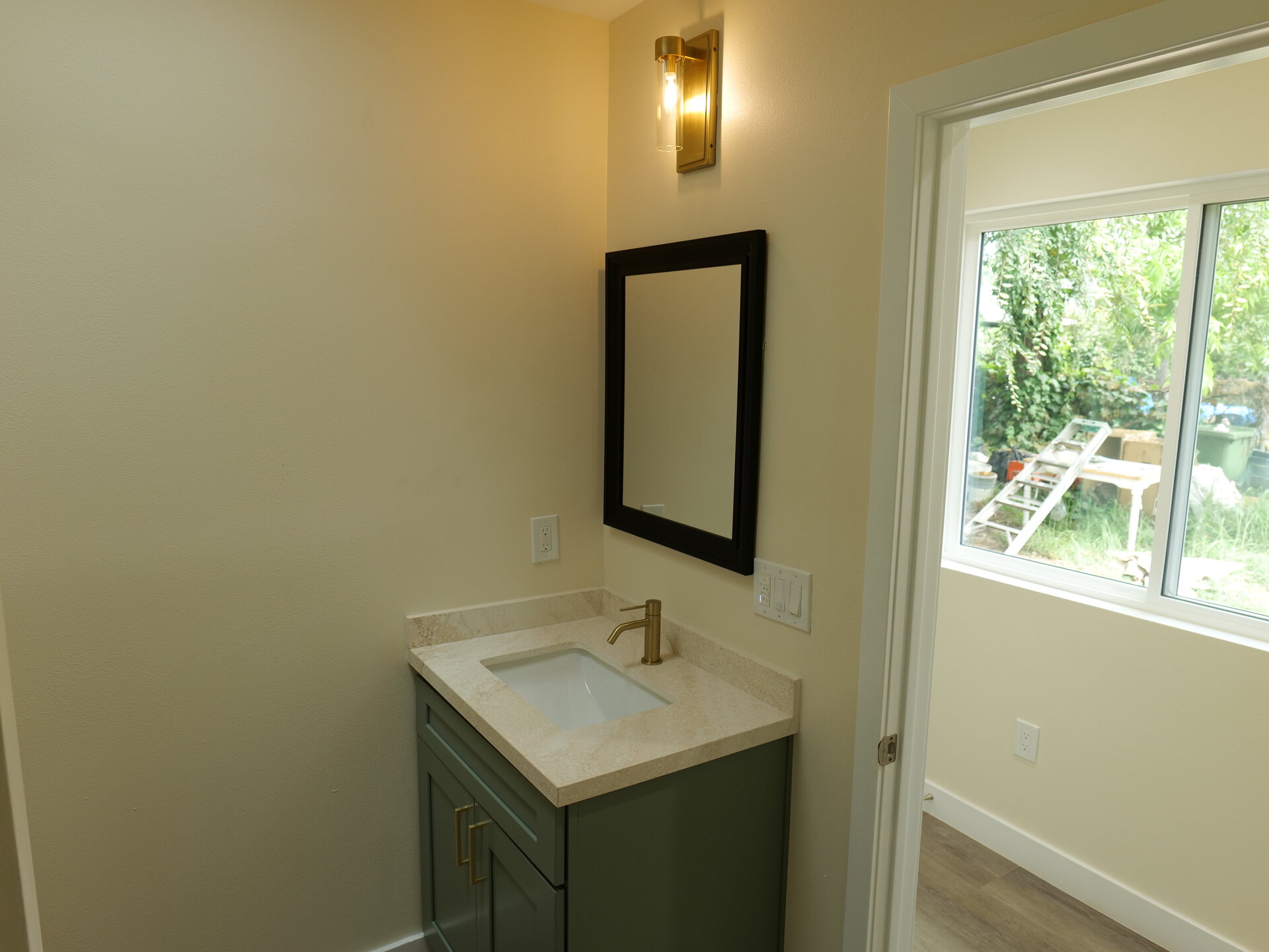 finished bathroom vanity with sink, mirror, wall light, and window