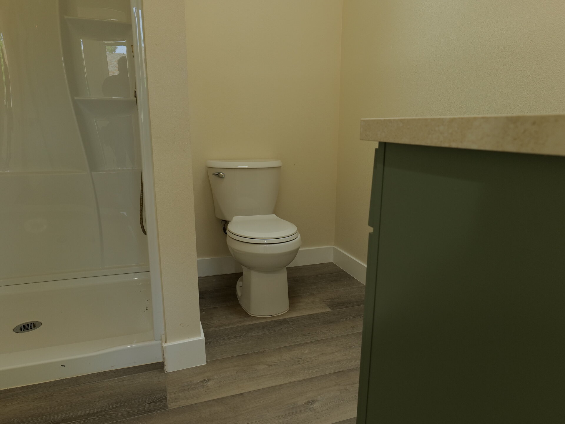 finished bathroom showing toilet, shower enclosure, and partial vanity