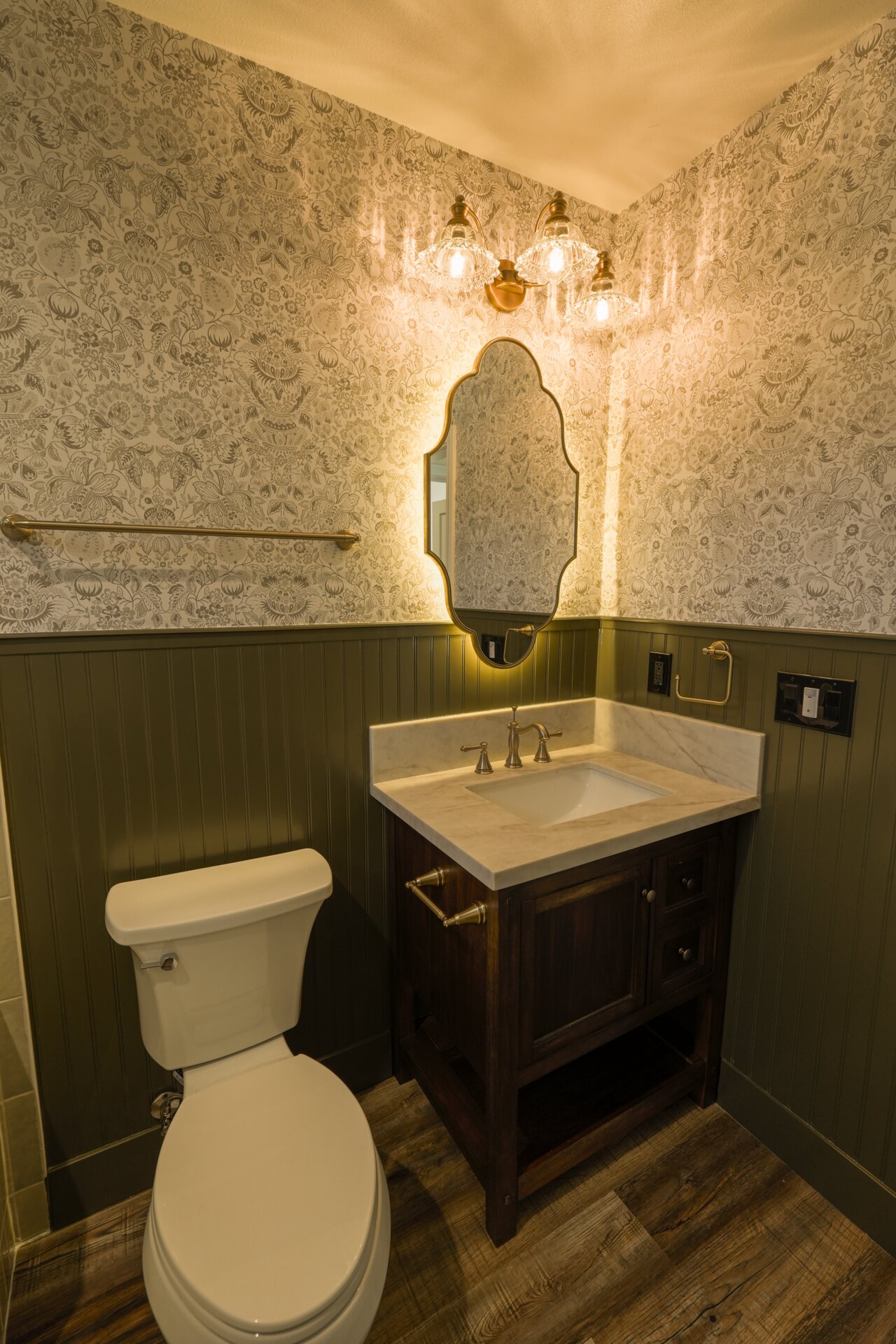 Bathroom vanity with an illuminated mirror and warm stone tile