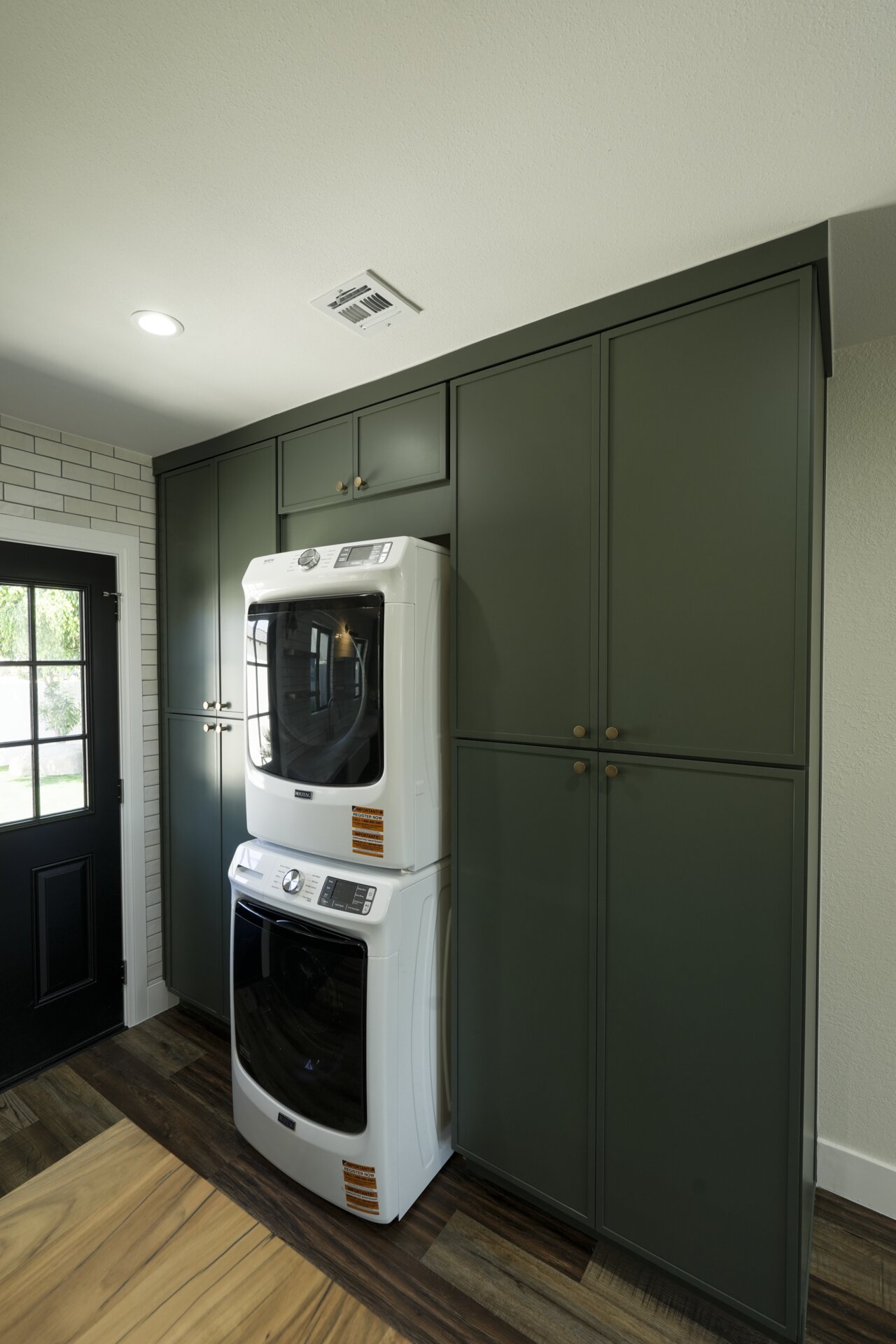 Deep green kitchen cabinetry with stainless steel appliances