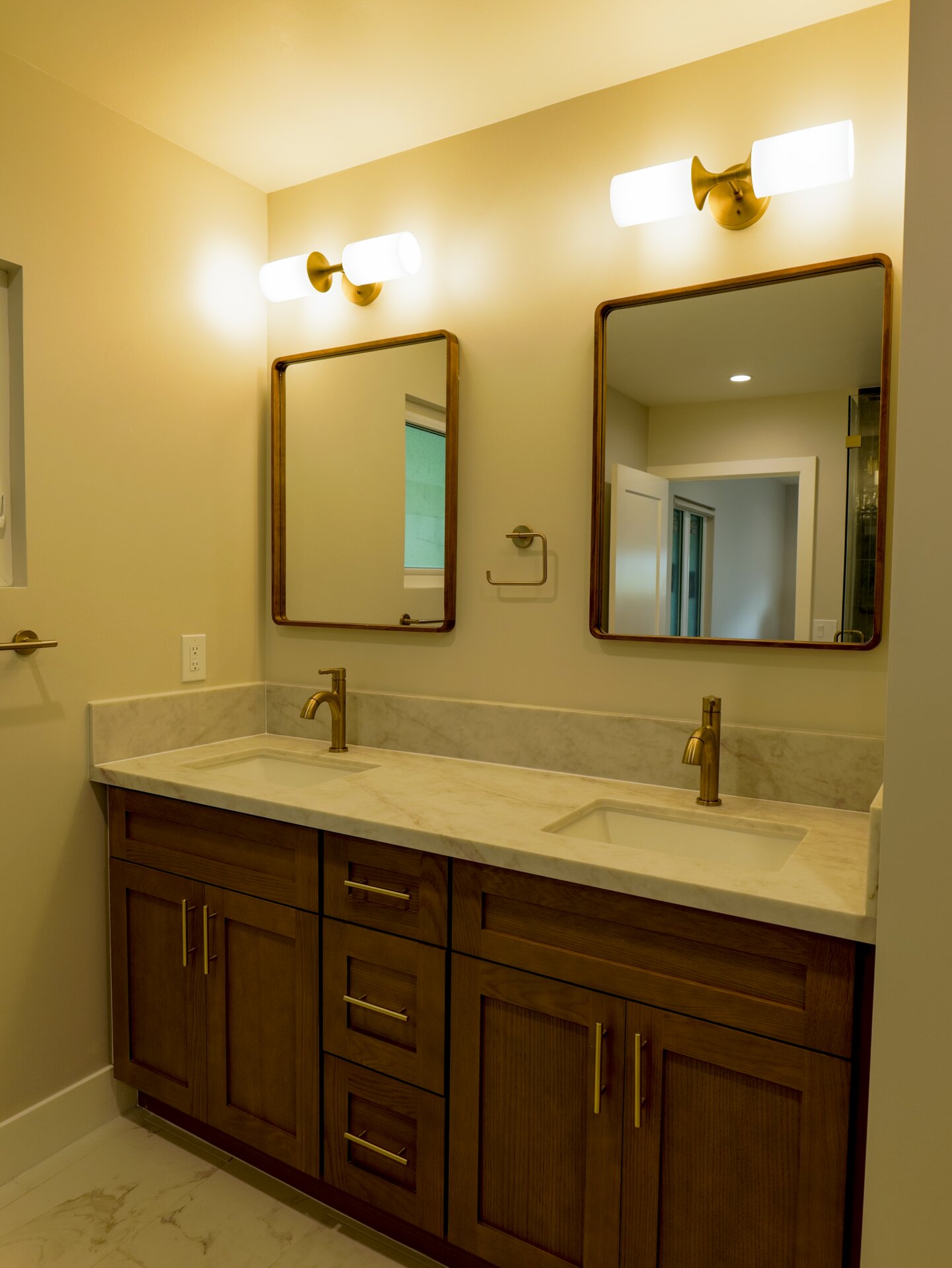 Large wood double vanity with twin mirrors and warm lighting
