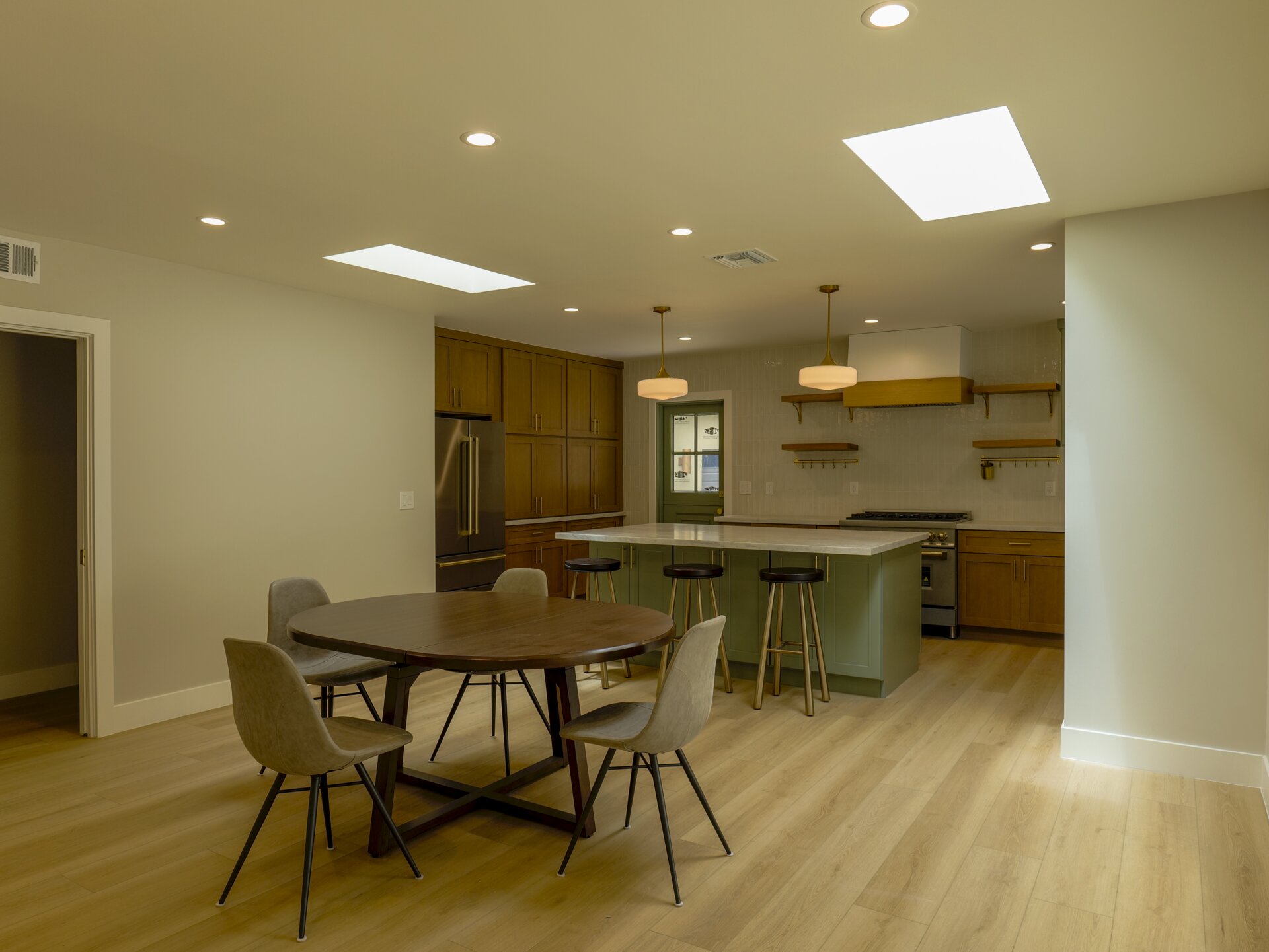 Open kitchen and dining space with a green island and wood cabinets