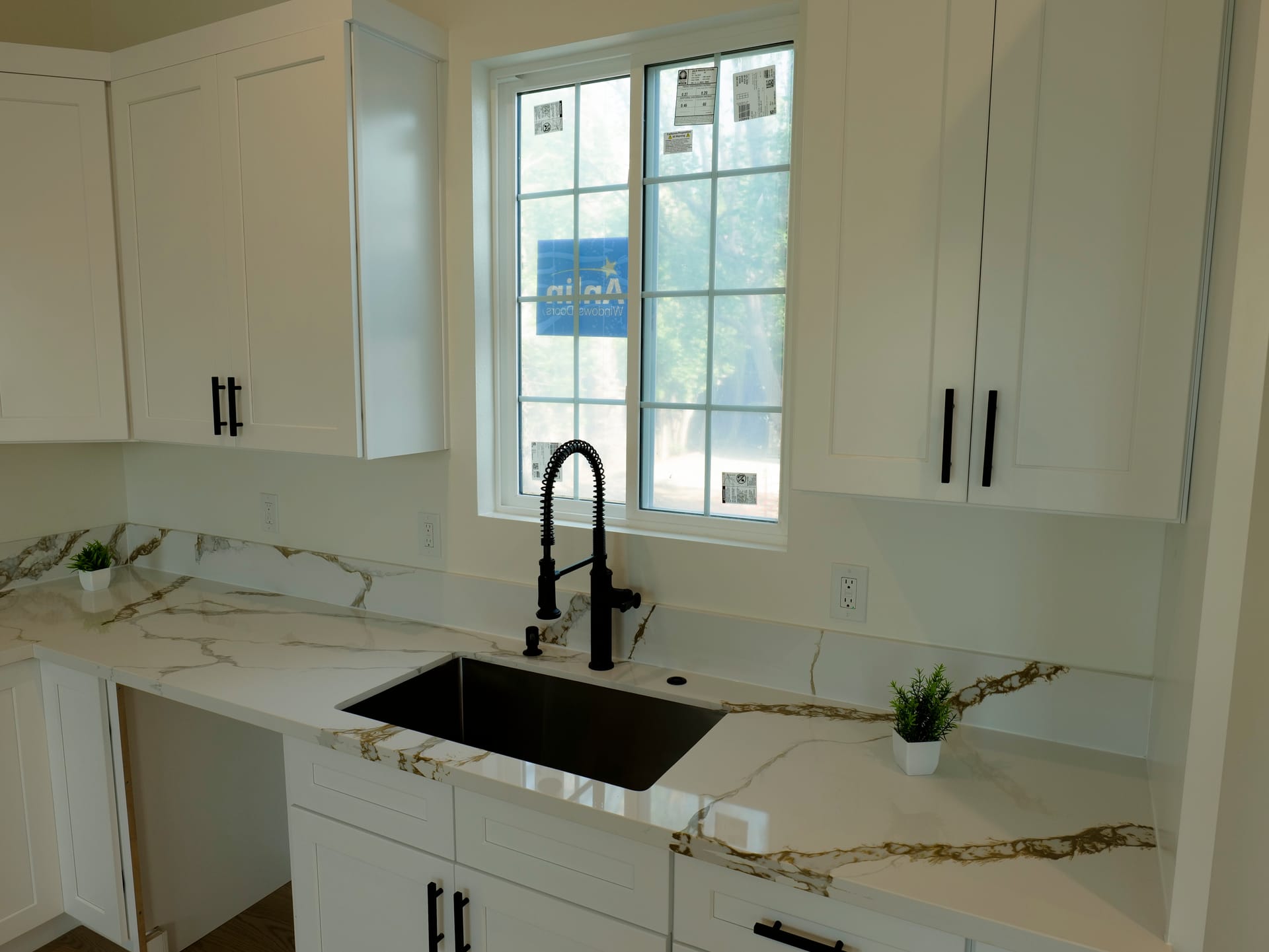 White kitchen countertop and dark faucet beneath a window