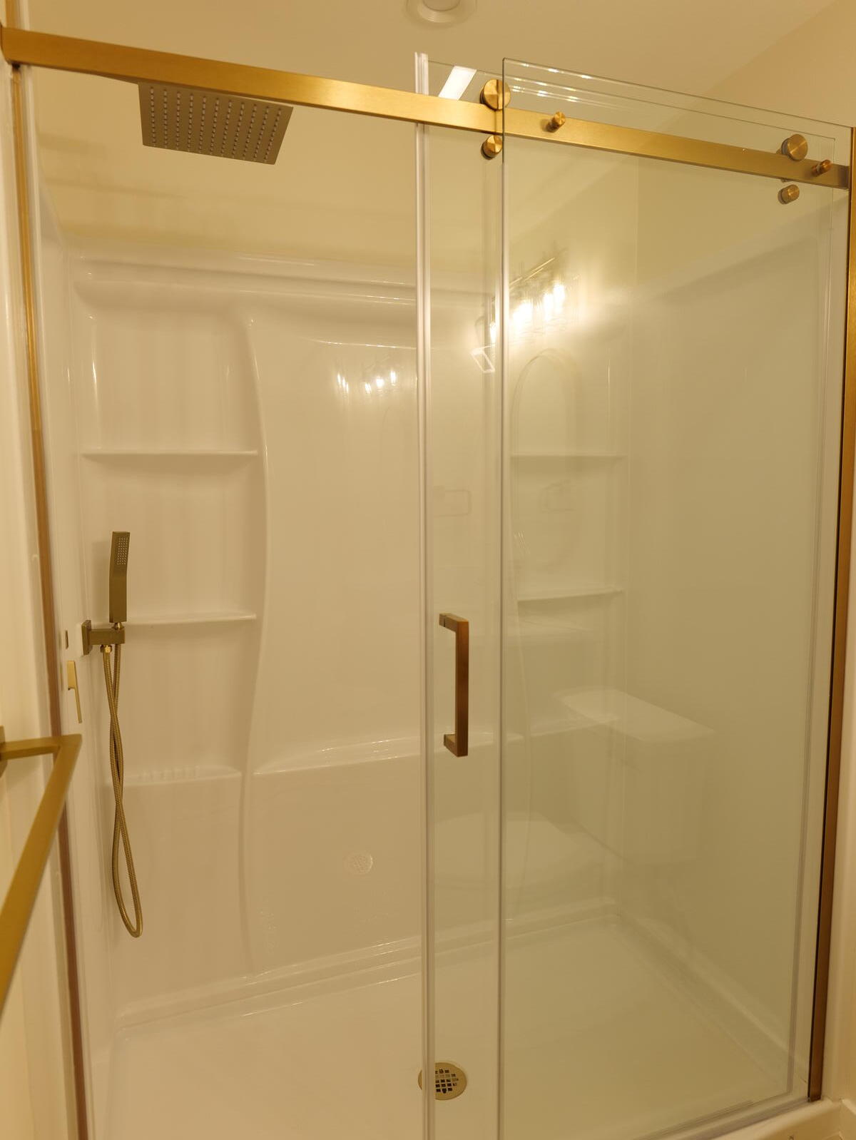 Glass shower enclosure with gold-toned hardware
