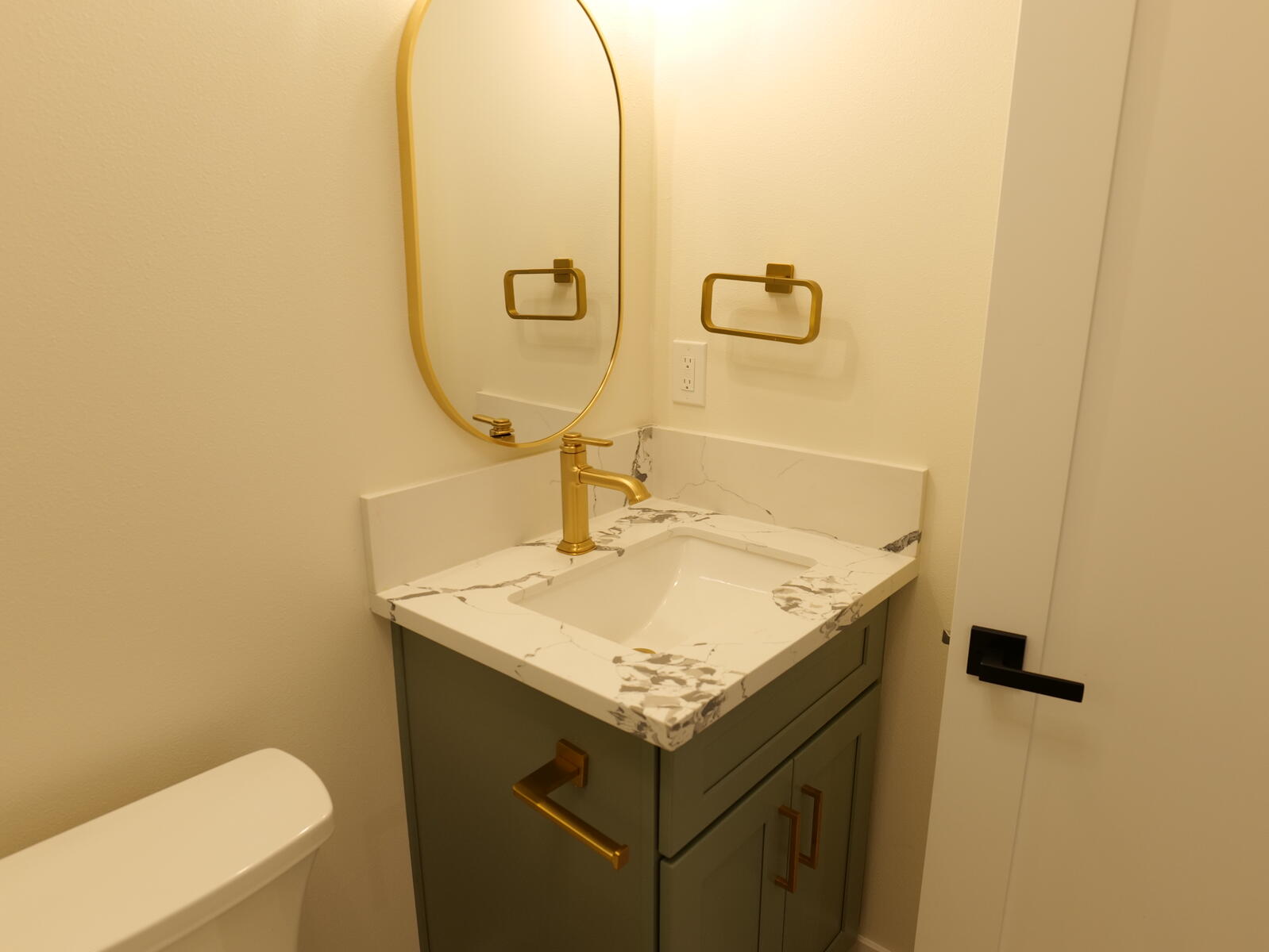 Gray vanity with a gold-framed mirror and matching fixtures
