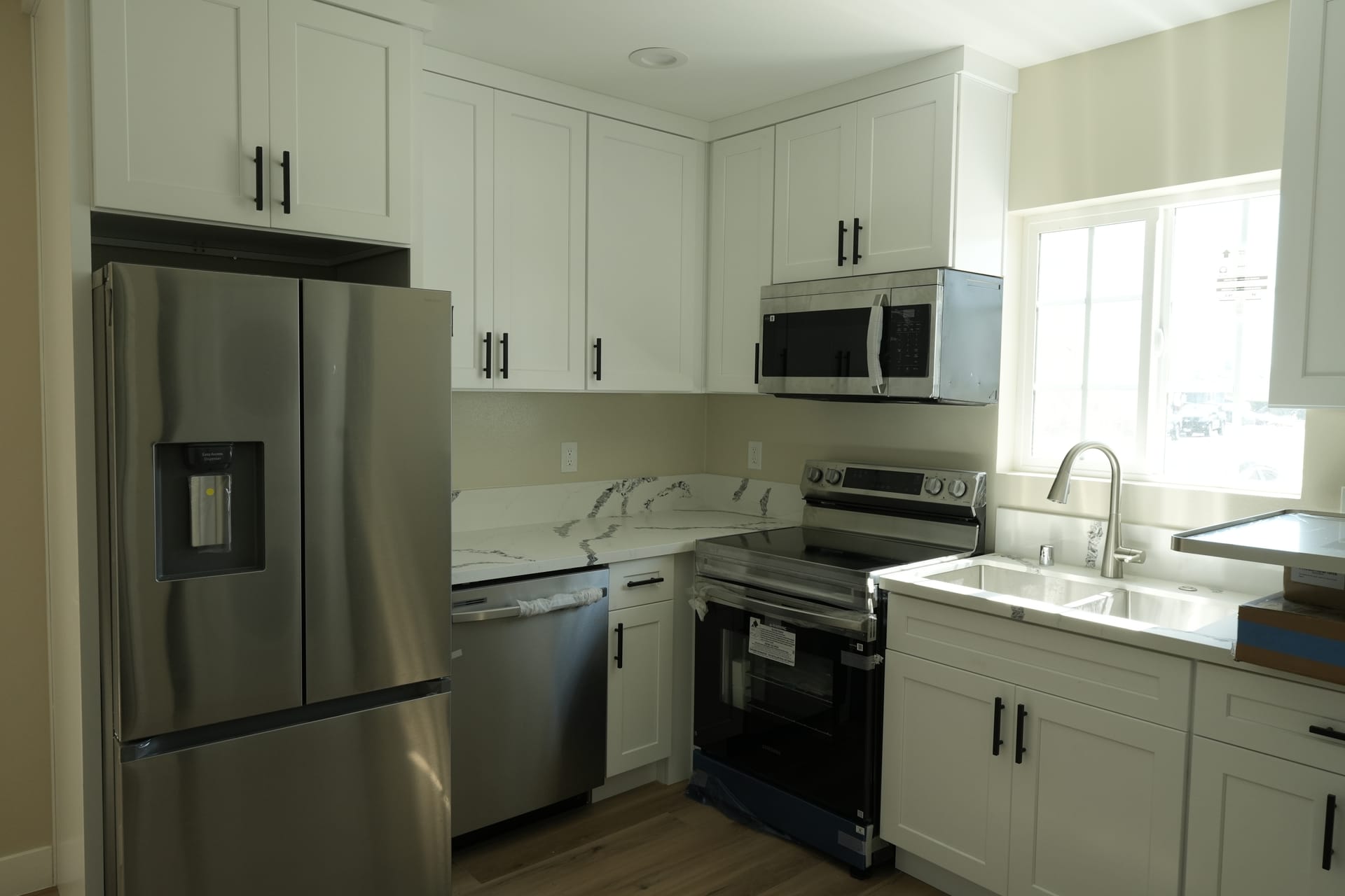White kitchen with stone-pattern counters and stainless steel appliances